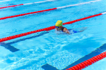 Swimmer child swims breaststroke swimming style in a race swimming pool. Water sports and competition, learning to swim classes for children.