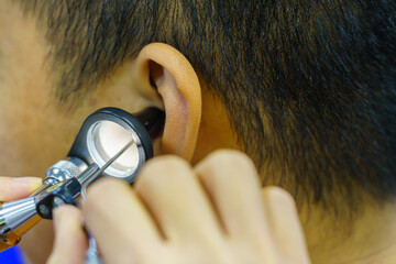Patient is seen by an otolaryngologist. ENT doctor examines a patient. An otolaryngologist examines a patient's inner ear using an otoscope. Treatment of inflammation disease of ears