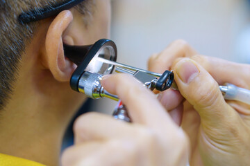 Patient is seen by an otolaryngologist. ENT doctor examines a patient. An otolaryngologist examines a patient's inner ear using an otoscope. Treatment of inflammation disease of ears