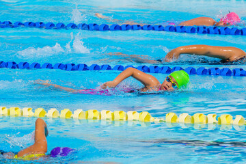 Swimmer child swims freestyle swimming style in a race swimming pool. Water sports and competition, learning to swim classes for children.
