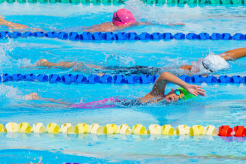 Swimmer child swims freestyle swimming style in a race swimming pool. Water sports and competition, learning to swim classes for children.