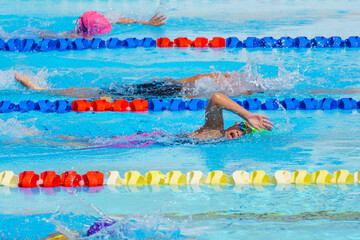 Swimmer child swims freestyle swimming style in a race swimming pool. Water sports and competition, learning to swim classes for children.