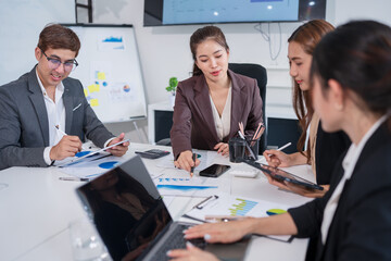 Group of Asian business people sitting in a meeting, with laptops and iPads on the table, planning investment, business strategy.