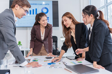 Group of Asian business people standing in a meeting, with tablets and iPads on the table, planning investment, business strategy.