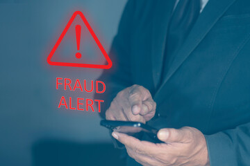Businessman using smartphone with triangle fraud alert caution warning sign bright red warning on a screen. Scam Alert Warning.