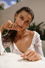 Close-up portrait of a woman with wet hair and natural makeup, her skin glowing in soft light. A...