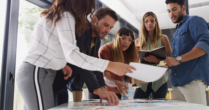 Creative business people, paperwork and planning in meeting for graphic designers. Group, document and discussion in startup office for color palette, brainstorming ideas and collaboration for design