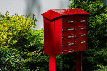 Bright red mailbox surrounded by lush greenery in a quiet neighborhood