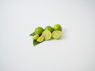 Fresh lime fruit group with slice detail and shadow contrast presented on a white surface to emphasize citrus freshness and health value