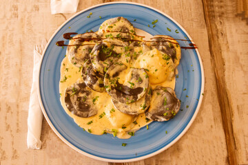 Black ravioli with lobster filling in creamy sauce. Top view