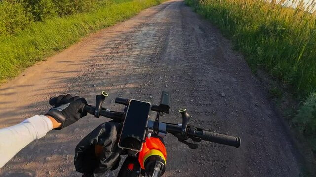 Cycling on a dirt country road in summer in a field at sunset