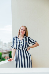 Beautiful blonde in summer striped dress laughing and rejoicing