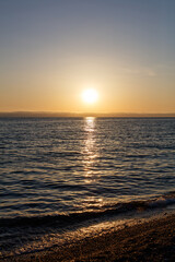 The sun is setting over the ocean, casting a warm glow on the water