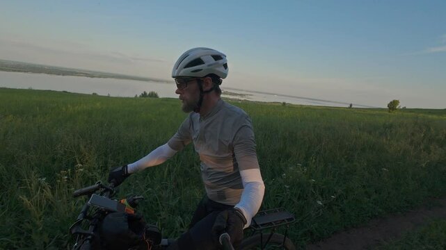 man riding bike at sunset outside city and filming video for blog, solo bike trip