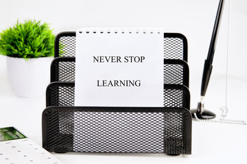 E-learning education concept. NEVER STOP LEARNING written message on a white sheet of paper in a...