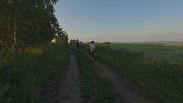 woman with daughter riding bicycles through fields, family trip