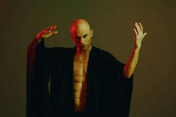 A striking man in a black robe poses dramatically with expressive hand gestures, creating an...