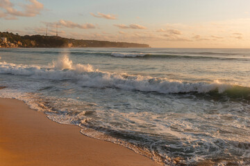 Raging ocean waves in the setting sun. Foamy waves wash the coast of the island of Bali. Vacation on a tropical island