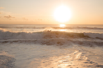 Surfer makes maneuvers and a bottom turn on a wave against the background of the setting sun. A surfer actively rides big waves in the ocean