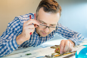 worker in a printing uses a magnifying glass