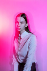 A young female model in the pink light in the studio