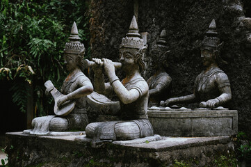 Obraz premium Ancient stone statues of traditional Thai musicians in forest temple