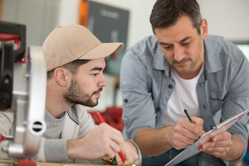 side view portrait of mature carpenter helping young worker