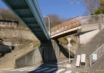 A view of a junction, featuring footbridges overhead for safety. The road winds through the town, and the residential area is situated on the upper part.