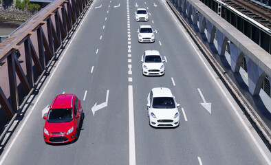 Concept of lateral thinking or disruptive thinking. The white cars are all headed in one direction but the red car explores other possibilities.