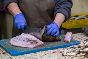 A seller cuts fresh flounder at a market stall