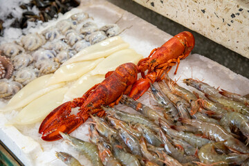 A vibrant display of fresh lobster and shrimp at the seafood market, alongside squid and clams on ice