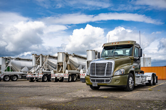 Fototapeta Khaki day cab big rig semi truck tractor standing on the industrial parking lot beside with bulk semi trailers waiting for the next load
