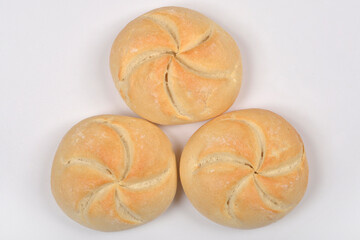 Three light brown kaiser rolls with their distinctive star-shaped tops are arranged on a simple...