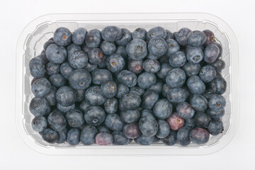 A plastic container filled with fresh, ripe blueberries is viewed from above against a neutral background