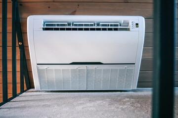 Close-up of modern Ballu air conditioner unit installed in cozy wooden interior, front view with...