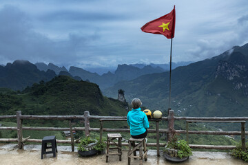 Solo female traveler enjoying the scenic view of mountainous landscape of Ha Giang valley in northern Vietnam