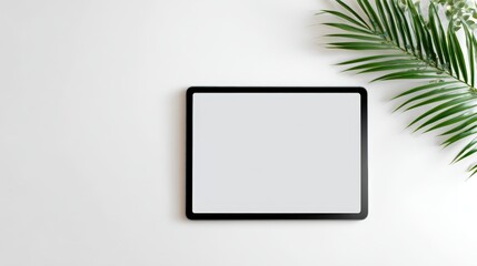 Mock up of a sleek black tablet device with a blank screen positioned on a clean white surface, surrounded by green palm leaves, ideal for showcasing digital content or design projects