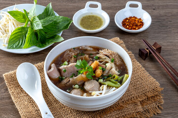Stewed Beef And Offal Noodle Soup, A Thai Street Food Dish, And Vegetables In A Bowl On A Wooden Table