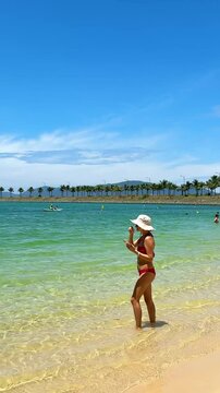 Beautiful girl in pink swimsuit posing on the beach, taking pictures and photos, slim figure, girl in red ikini, clean ocean, beautiful beach