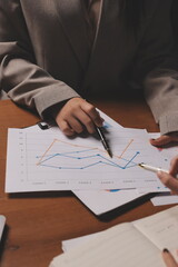 Naklejka premium Group of confident business people point to graphs and charts to analyze market data, balance sheet, account, net profit to plan new sales strategies to increase production capacity.
