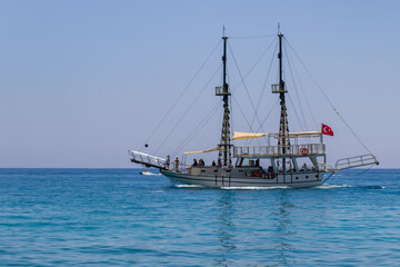 Tekirova, Turkey - June 7, 2025: Sailboat with people sails through the Mediterranean sea, crystal turquoise water