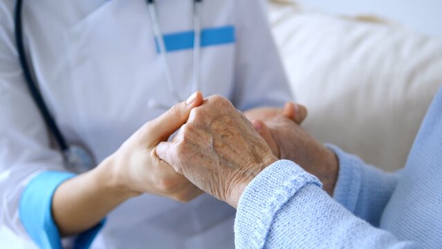 Close up capturing a doctor gently holding the hand of an elderly patient, providing comfort and reassurance during a medical visit, embodying empathy and connection in healthcare