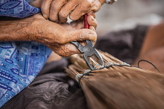 Close-up of Thai artisan clamping broom tightly