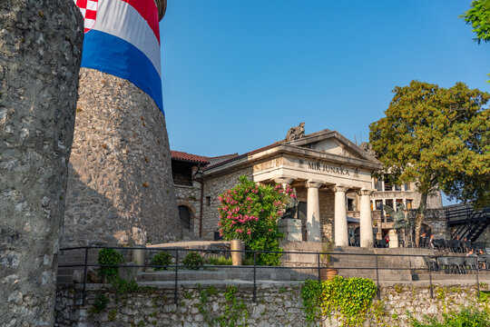 Wide-angle view of the &ldquo;Mir Junaka&rdquo; complex in Trsat, Rijeka, including stone columns, dragon sculptures, and a tower draped with the Croatian flag