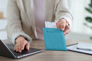 Travel agent with passport and ticket at wooden table in office, closeup