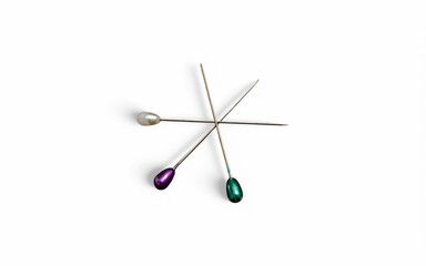 Three pins with colored heads lay crisscrossed on a stark white background, casting subtle shadows.
