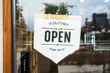 Sign text hangs on the entrance door of the shop, restaurant, cafe. That reads "Open". Business concept