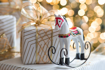 Stylish gift boxes, a horse and a Christmas tree in the home interior of the living room. A cozy concept for the Christmas holidays in 2026. We prepare gifts for our loved ones.