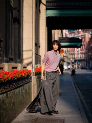 Portrait of handsome Chinese young man wearing gray suit posing in the street, young guy with black curly hair with urban background. Male fashion, cool Asian young man lifestyle.
