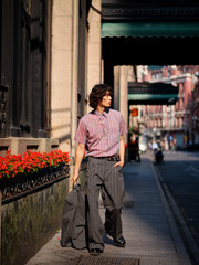 Portrait of handsome Chinese young man wearing gray suit posing in the street, young guy with black curly hair with urban background. Male fashion, cool Asian young man lifestyle.